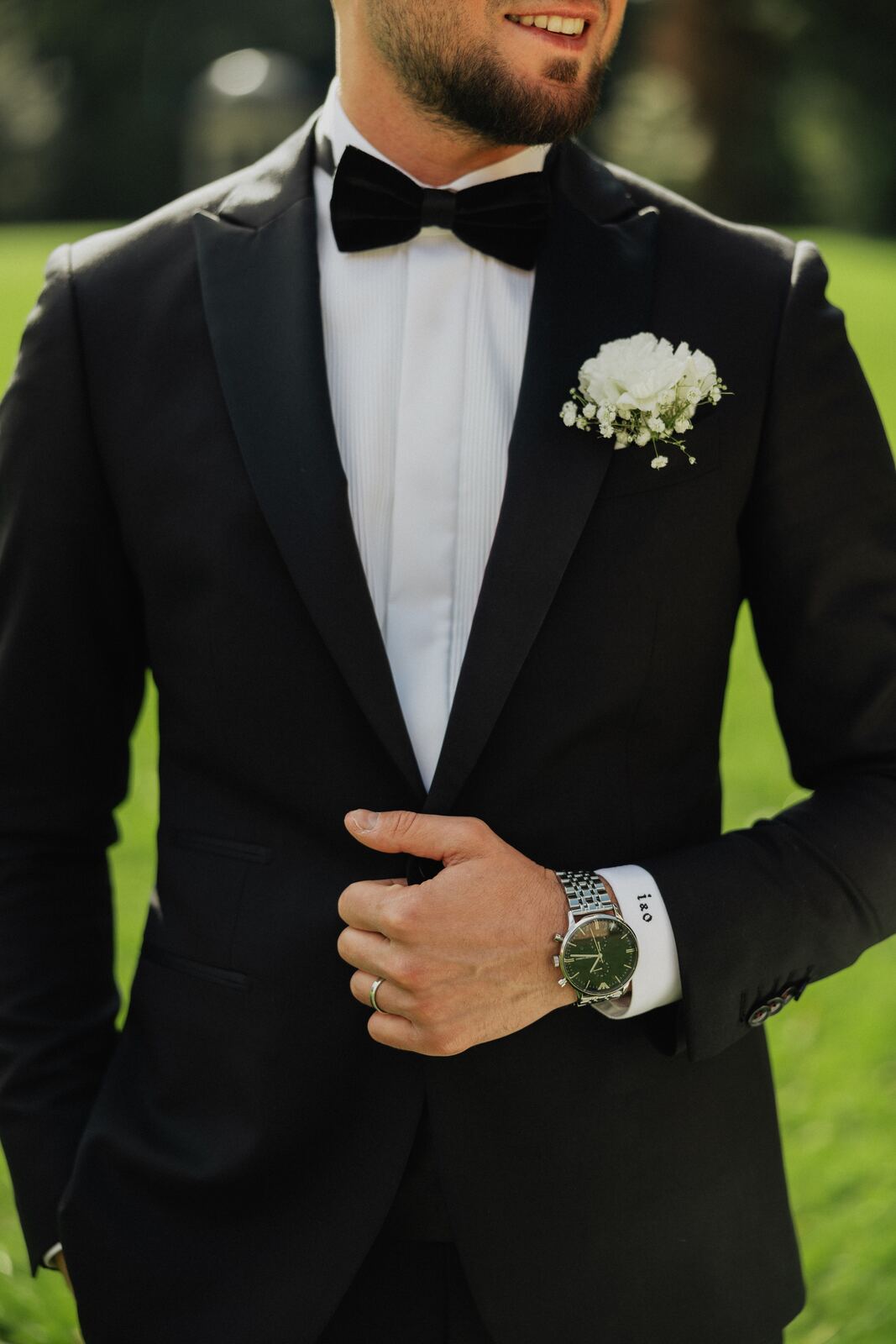 Bruidegom in smoking met strik en corsage die zijn jasje rechtzet
